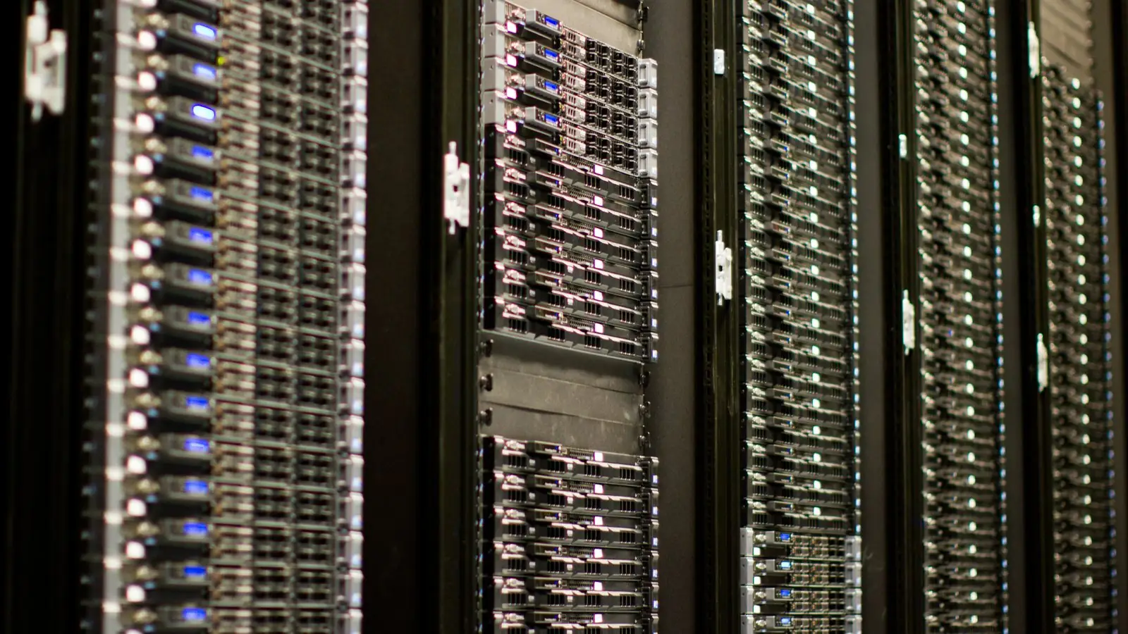 File photo from July 2012: racks of Wikimedia Foundation servers, rows of rack-mounted machines with blue and white status lights.